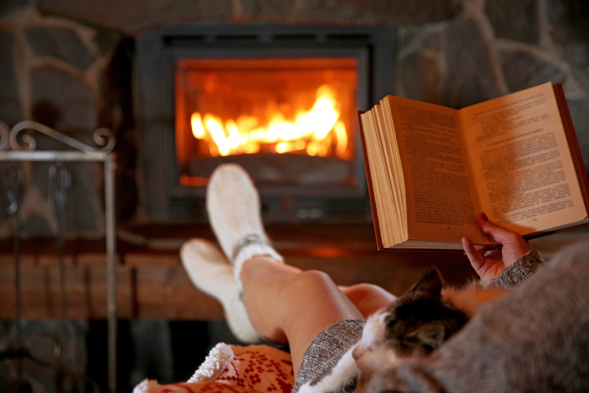 Woman Resting with Book near Fireplace